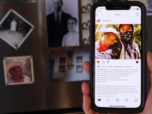 Photo of a hand holding up a cell phone with an image of two people.